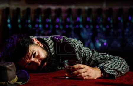 Photo for Upset bearded man drinker alcoholic sitting at bar counter with glass drinking whiskey alone. Sad depressed addicted drunk guy having problem from alcohol addiction abuse, alcoholism - Royalty Free Image