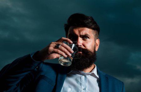 Luxury rich bearded man drink expensive beverage. Man with beard holds glass brandy, drink cognac. Guy hipster tastes drink. Sipping whiskey. Nightlife