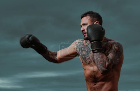 Téléchargez les photos : Coup de pied musclé boxeur ou muay thai boxeur poinçonnage. Combattant de kickboxing en gants de boxe frappant l'ombre, s'entraînant pour la compétition. Boxer punch - en image libre de droit