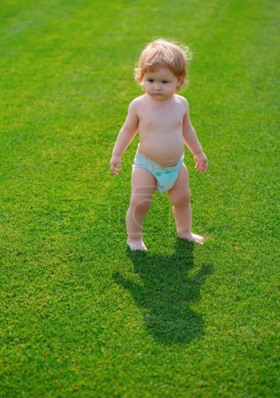 Photo for Adorable baby boy outdoors posing on green grass. Summer portrait of beautiful child on the lawn - Royalty Free Image