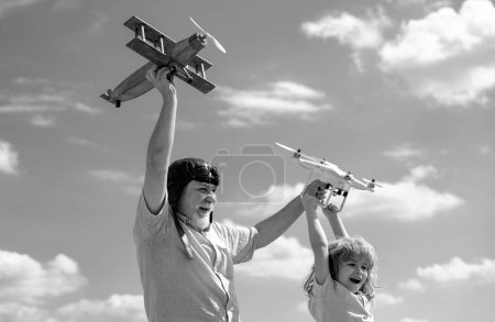 Téléchargez les photos : Grand-père et fils avec avion et drone quadcopter sur fond bleu ciel et nuages. Hommes génération grand-père et petit-enfant. Aîné parent âgé avec enfant - en image libre de droit