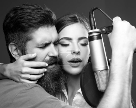 Photo for Singer couple singing rock. Sound producer recording song in a music studio. Sexy man and woman singing with music microphone - Royalty Free Image