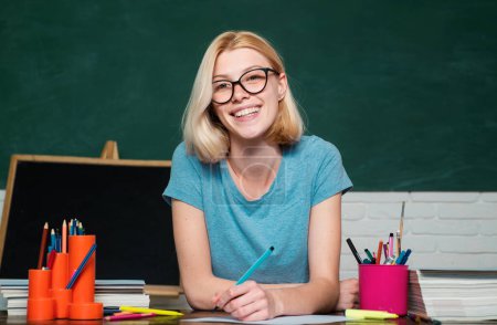 Photo for Smiling girl student or woman teacher portrait on green wall blackboard background. Portrait of college student in college. High school concept - copy space - Royalty Free Image