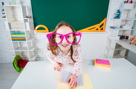 Photo for Funny schoolgirl preschool with fun glasses in school near blackboard - Royalty Free Image