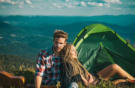 Photo for Romantic couple camping outdoors and sitting near tent. Happy Man and woman on a romantic camping vacation. Young couple in love hug each other - Royalty Free Image