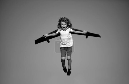 Photo for Child to be pilot. Kid with paper wings flying. Summer vacation and travel concept. Funny child boy with toy cardboard airplane wings fly on sky. Kids dreams of traveling in summer in nature - Royalty Free Image