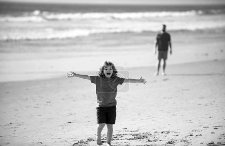 Téléchargez les photos : Petit garçon marchant vers la plage, les mains levées. Incroyable surpris enfants émotions. - en image libre de droit