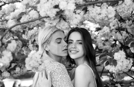 Foto de Chicas de primavera. Una pareja de lesbianas besándose. Hermosa mujer joven sexy primavera con flores de sakura. Un beso sensual. Lgbt - Imagen libre de derechos