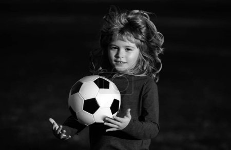 Téléchargez les photos : Soccer enfant jouer au football. Garçon tenant ballon de soccer, portrait d'enfants sportifs de gros plan - en image libre de droit