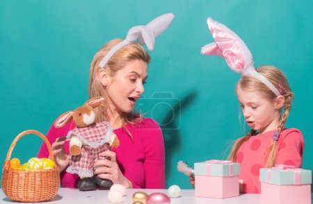 Foto de Feliz Pascua. Madre e hija comienzan a cazar huevos de Pascua. Familia feliz preparándose para la Pascua. Linda niña usando orejas de conejo en el día de Pascua - Imagen libre de derechos