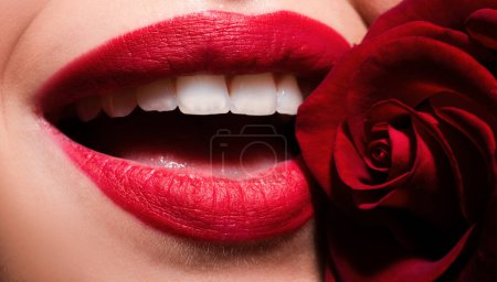 Foto de Hermosos labios de mujer con rosa. Boca abierta con dientes blancos. Cosmetología, farmacia o concepto de maquillaje de moda. Estudio de belleza filmado. Boca apasionada - Imagen libre de derechos