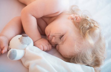 Foto de Hermoso bebé lindo durmiendo en la cama en casa con juguete, niño durmiendo en la cama - Imagen libre de derechos