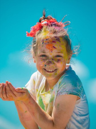 Téléchargez les photos : Le festival Kid Holi. Visage peint d'un enfant drôle. Petit garçon joue avec les couleurs - en image libre de droit