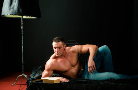 Foto de Sexy bodybuilder athlet, con torso desnudo se encuentra en la cama en el interier de lujo - Imagen libre de derechos