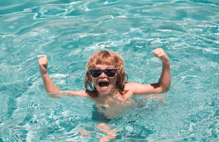 Téléchargez les photos : Enfant dans la piscine d'été. Mignon petit garçon excité dans les lunettes de soleil dans la piscine dans la journée ensoleillée - en image libre de droit