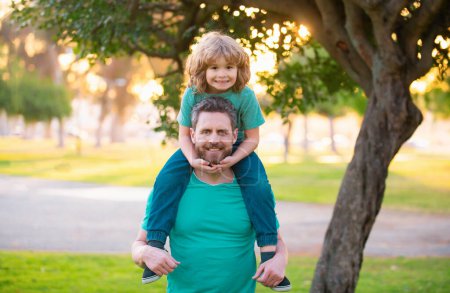 Photo for Happy father and son enjoying summer time on vacation in a sunny park. Dad carrying on shoulders happy little boy - Royalty Free Image