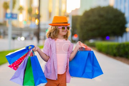 Téléchargez les photos : Enfant avec sacs à provisions. Mode et vente. Achats, vente et concept de consommateur - en image libre de droit
