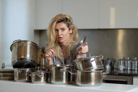 Téléchargez les photos : Femme au foyer cuisinant à la cuisine. Femme a préparé la nourriture le matin avec des casseroles - en image libre de droit