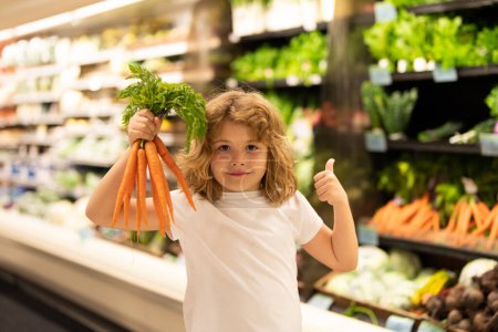 Téléchargez les photos : Enfant choisissant des légumes dans un magasin de supermarché. Des enfants dans un supermarché. Ventes, réductions dans les supermarchés alimentaires et achats. Enfant dans la baie du marché légumes et fruits. Enfant acheter au supermarché - en image libre de droit