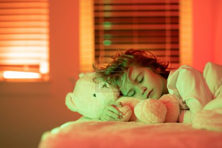 Photo for Bedding child. Cute kid sleeps with a toy teddy bear in bed. Sleeping child - Royalty Free Image