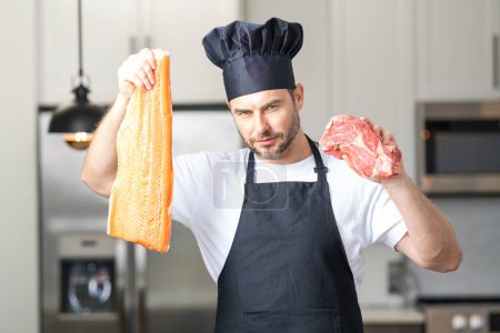 Photo for Health, natural protein concept. Handsome man in kitchen cooking fish and meat, salmon and beef in the kitchen. Healthy food concept. Healthy diet, meat protein - Royalty Free Image