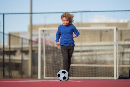 Child boy hold classic soccer ball on playground. Kid holding football ball in studio. Kid playing with ball. Sport, soccer hobby for kids. Little football player posing with soccer ball