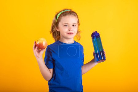 Photo for Kids sport. Sporty kids boy. Portrait of Kid boy hold bottle water and apples. Kid boy after sports isolated on yellow studio background. Fitness kids. Healthy child active lifestyles - Royalty Free Image