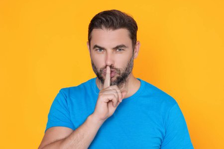 Photo for Shh man. Portrait of man showing shh taboo sign with finger to lips over yellow studio background. The secret. Hush shut silent Concept. Mute and quiet, finger on mouth shush sign. Silence gesture - Royalty Free Image