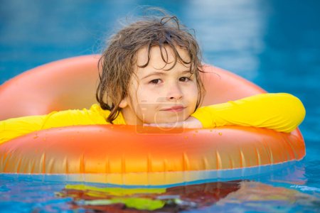 Téléchargez les photos : Enfant jouant avec l'anneau gonflable dans la piscine le jour d'été. Petit enfant nageant dans la piscine. Enfant dans la piscine se détendre et nager sur anneau gonflable. Concept vacances d'été. Vacances d'été - en image libre de droit