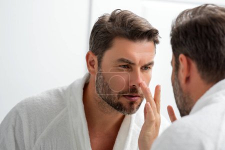 Photo for Beauty face portrait of a beautiful man applying face cream. Moisturizing skincare cream for man. Mask, skin lifting and anti-aging effect. Beauty male face concept. Skincare and aging. Face cosmetic - Royalty Free Image