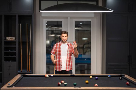 Photo for Man Playing billiard. Man trying to hit the ball in billiard in Billiard room. Russian pool billiards. Snooker Player. Young professional man playing billiards in the dark billiard club - Royalty Free Image