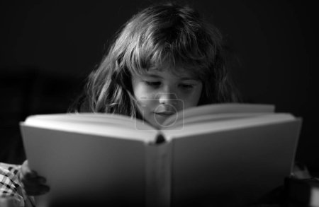 Foto de Feliz infancia, niño soñador. Un niño lindo leyendo un libro acostado en la cama - Imagen libre de derechos