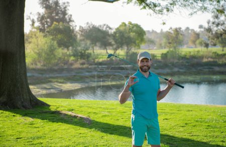 Portrait of happy smilin golfer hitting golf shot with club on course