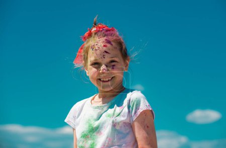 Téléchargez les photos : Festival de couleurs Kids Holi. Visage peint d'un enfant souriant. Petite fille joue avec les couleurs - en image libre de droit