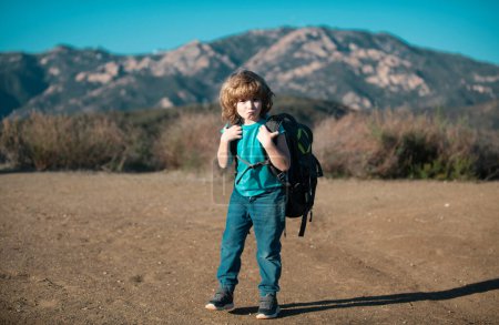 Kid with backpack hiking in scenic mountains. Boy local tourist goes on a local hike