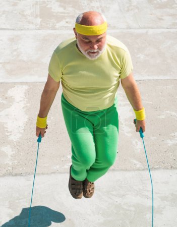 Téléchargez les photos : Un vieil homme qui saute la corde. Fitness senior homme sauter avec une corde à sauter à l'extérieur - en image libre de droit