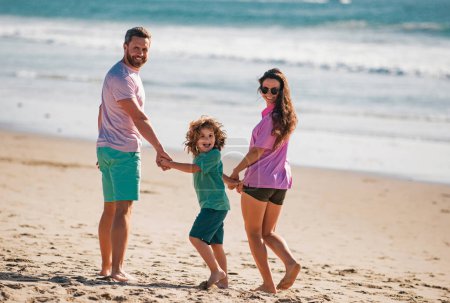 Foto de Paseo familiar por la playa del mar. Padres felices con niños jugando en la playa. Pasar el verano en la naturaleza - Imagen libre de derechos