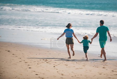 Foto de Familia feliz corriendo en la playa al atardecer. Concepto de viaje familiar. Personas sanas - Imagen libre de derechos