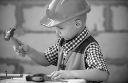 Foto de Retrato de pequeño constructor en sombreros con instrumentos para la renovación en la construcción. Constructor, carpintero con herramientas de construcción. Constructor y reparación de niños - Imagen libre de derechos