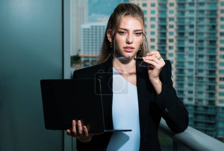 Téléchargez les photos : Sexy busines confiance femme en costume d'affaires de mode en utilisant un ordinateur portable au bureau. Fille à la mode en vêtements à la mode, portrait de style de vie de rue de la ville - en image libre de droit