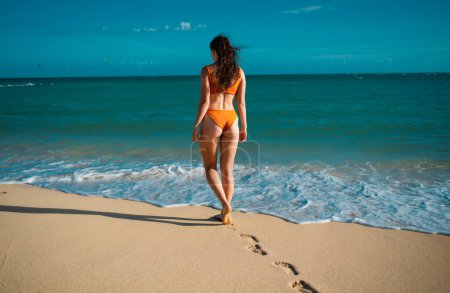 Foto de Mujer relajada en bikini disfrutando de la playa tropical y las vacaciones de verano. Fit chica bronceada disfrutando de un paseo por el mar - Imagen libre de derechos