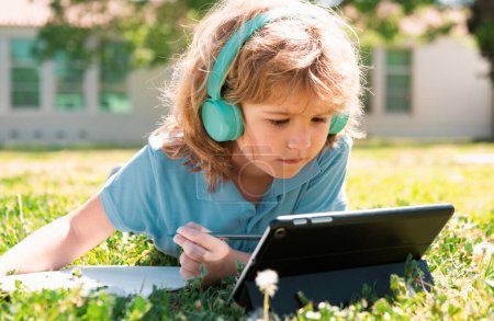 Photo for Cute american toddler school kid online learning, writing book in the park. Study outdoor - Royalty Free Image