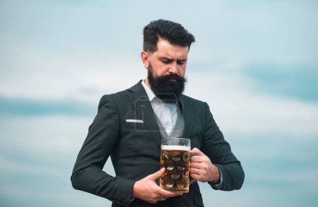 Téléchargez les photos : Un homme en costume classique buvant de la bière. Portrait d'homme avec haut verre de bière levé - en image libre de droit
