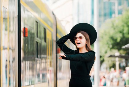 Foto de Hermosa modelo femenina corriendo después de trolebús de autobús en la ciudad de verano en Europa. Mujer de moda posando en el fondo de la calle. Viajar por la ciudad - Imagen libre de derechos