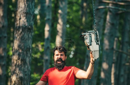 Photo for Lumberjack with chainsaw on forest background. Lumberjack worker with chainsaw in the forest. Man doing mans job. Woodcutter with axe or chainsaw in the summer forest - Royalty Free Image