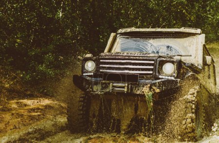 Photo for Motion the wheels tires and off-road that goes in the dust. Offroad vehicle coming out of a mud hole hazard. Off-road vehicle goes on mountain way. Rally racing - Royalty Free Image