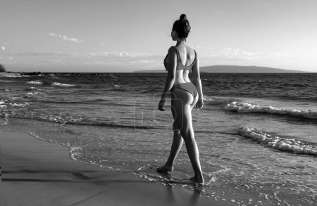 Foto de Hermosa mujer joven caminando en el mar en la playa de arena. Viaje de verano. Playa de verano y mar - Imagen libre de derechos