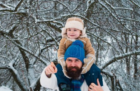 Photo for Merry Christmas and Happy New Year. Portrait of happy father giving son piggyback ride on his shoulders and looking up. Child sits on the shoulders of his father - Royalty Free Image