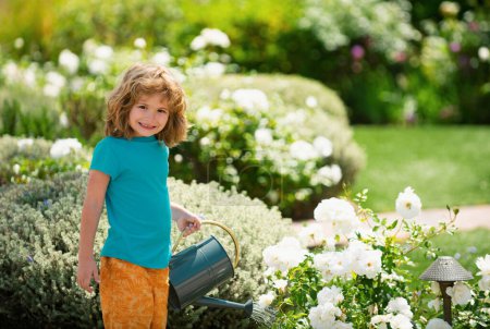 Téléchargez les photos : Kid aide à prendre soin des plantes dans le jardin. Petit garçon avec un arrosoir sur la cour. Concept d'activité d'apprentissage de la culture végétale pour les écoliers. Éducation des enfants de la nature - en image libre de droit