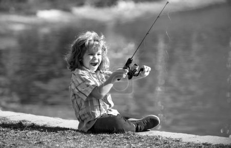 Foto de Emocionado niño sorprendido sentado cerca del lago y la pesca - Imagen libre de derechos